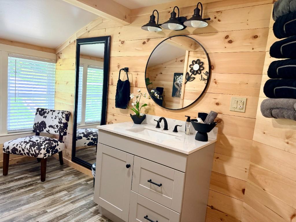 Blue Ridge Haven — Full bathroom vanity with round mirror, wood walls, and towel storage