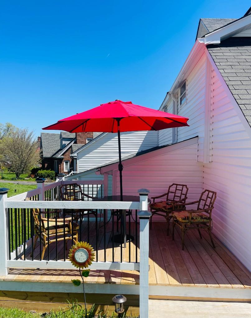 Fiddlers Roost — Private deck with dining table, floral chairs, and red umbrella