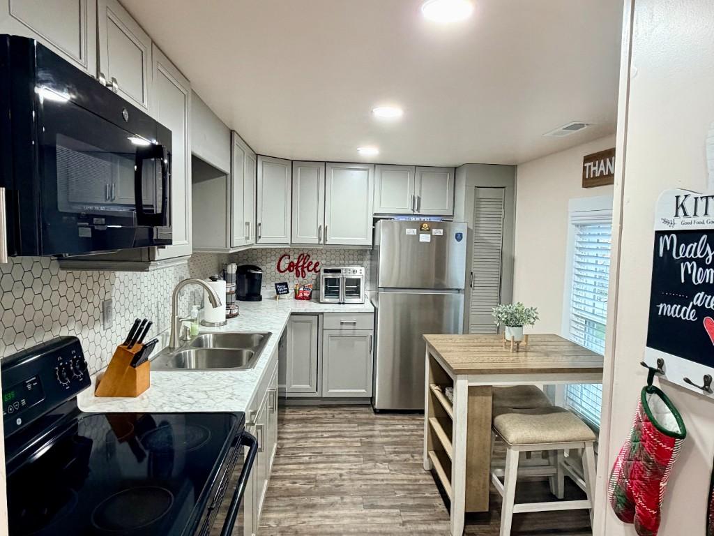 Fiddlers Roost kitchen with grey cabinets, hex tile backsplash, and dining nook