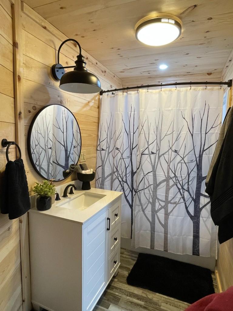 New River Hideaway bathroom with vanity, round mirror, and shower