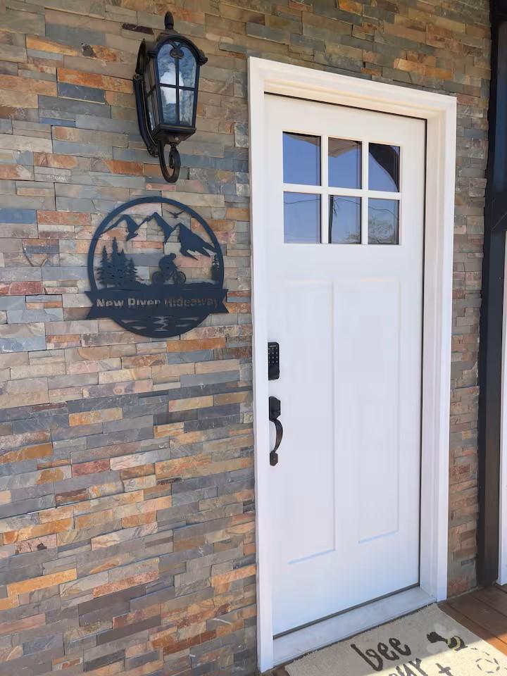 New River Hideaway entrance with stone wall and unit sign